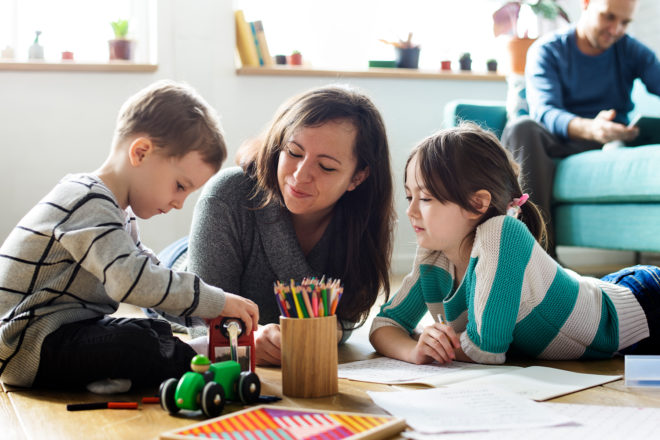 Mom sitting on living room floor with children