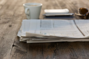 Newpaper sitting by coffee cup on table