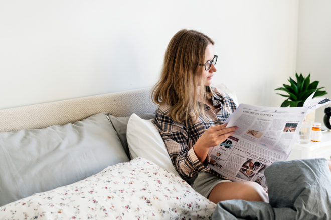 Woman reading news in bedroom of house