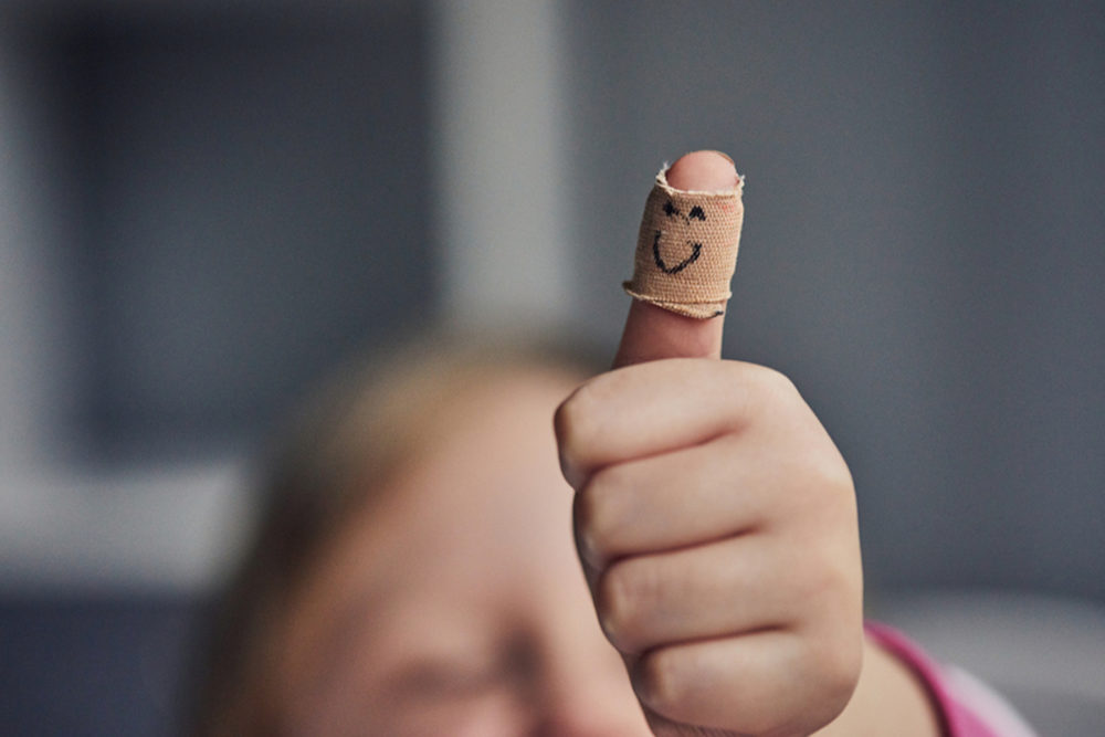 Child's bandaged thumb with smiley face