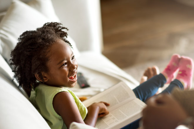 Child reading book with adult