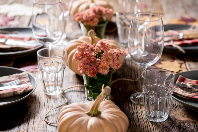 Fall table decorated for dinner with pumpkins, leaves and flowers