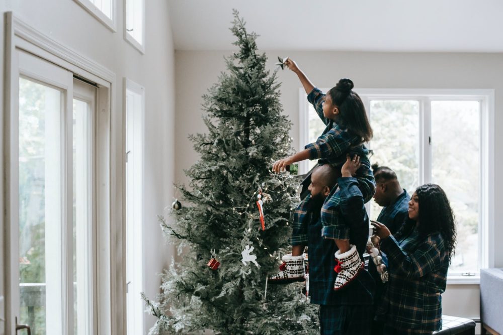 Family hanging holiday ornaments on a tree