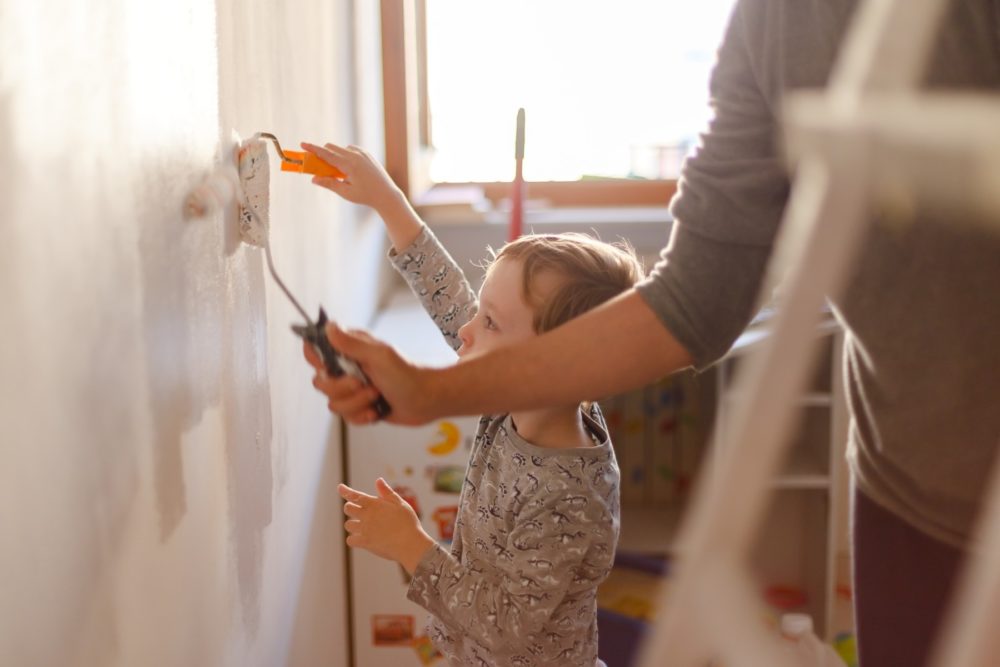 Child and mother paint a wall at home