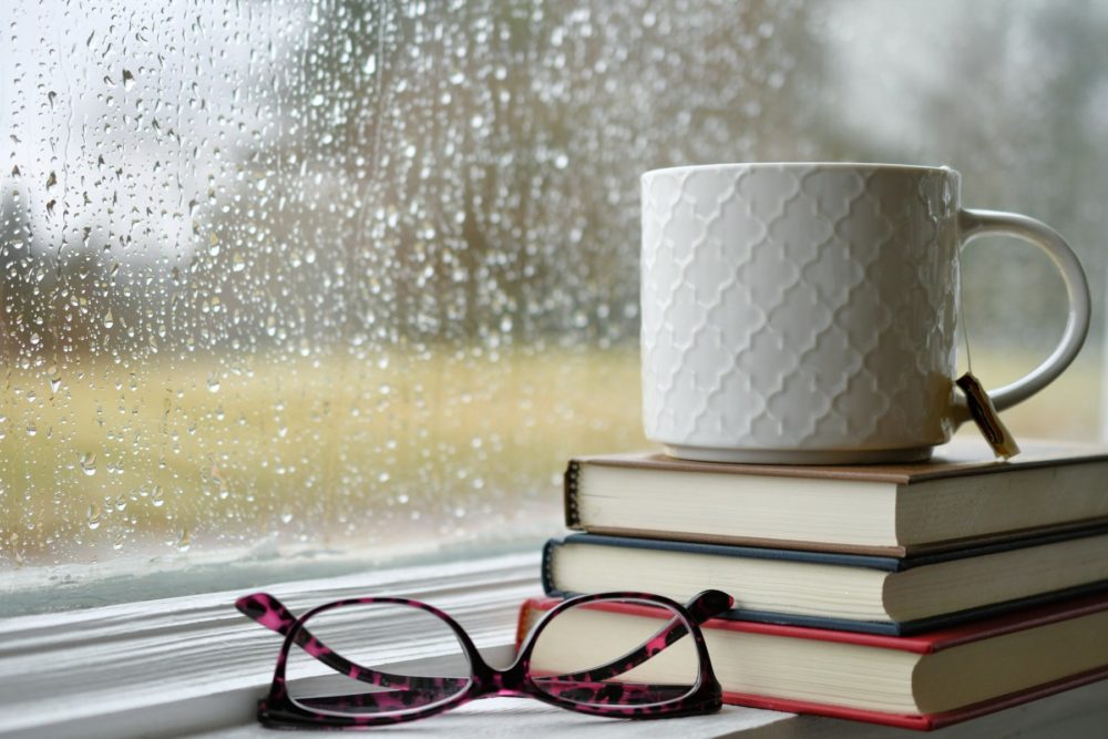 A pair of reading glasses by book and tea