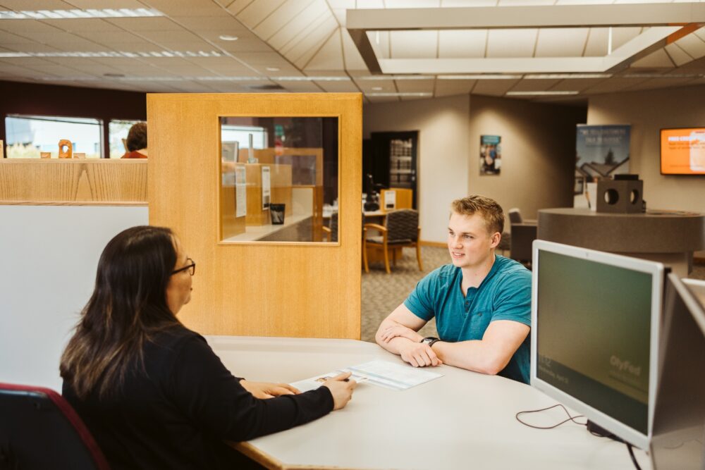 Trina sitting with a customer opening a checking account.