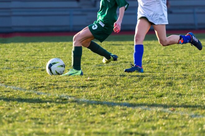 two players competing for ball on soccer field