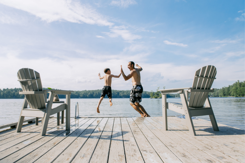 Man and boy give high 5 as they jump from dock into river