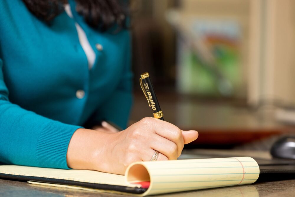A woman writing on a legal pad with a pen