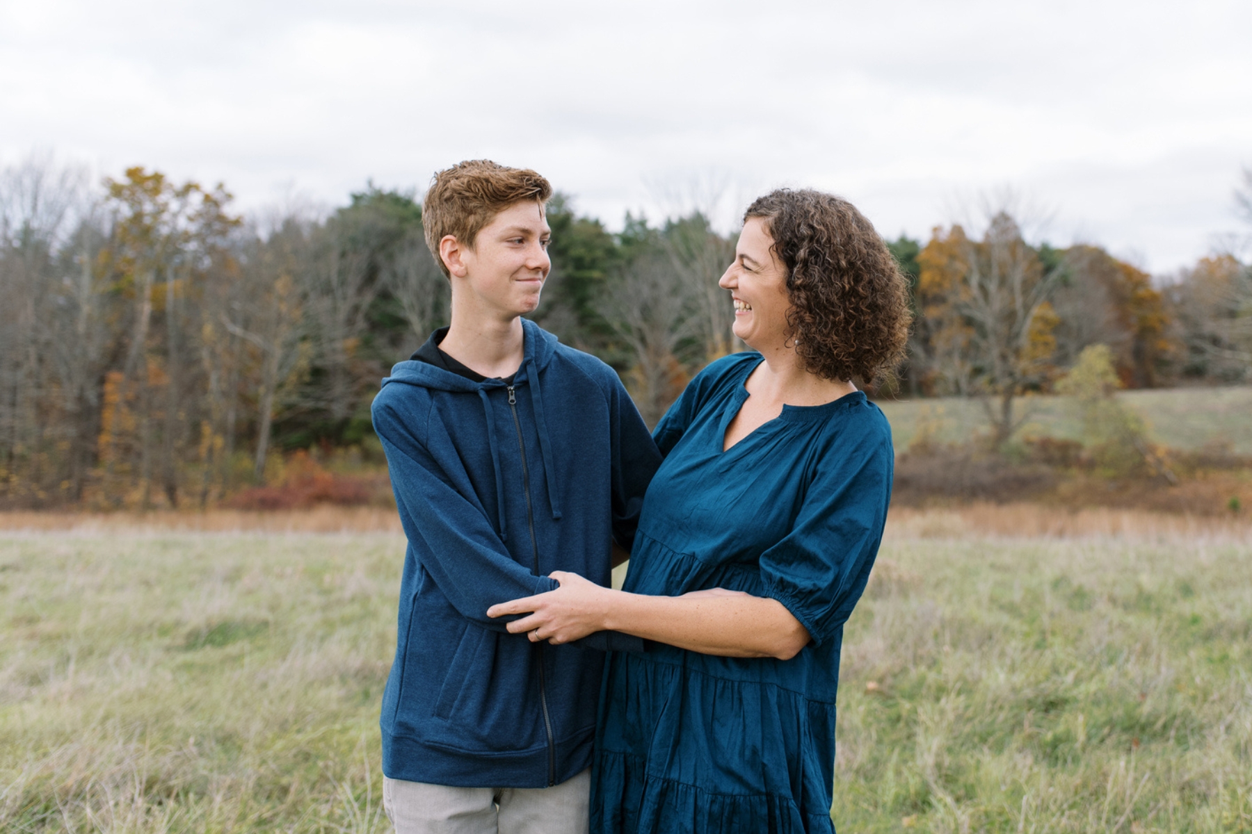 A mother posing for a picture with her teenage son for a family portrait.