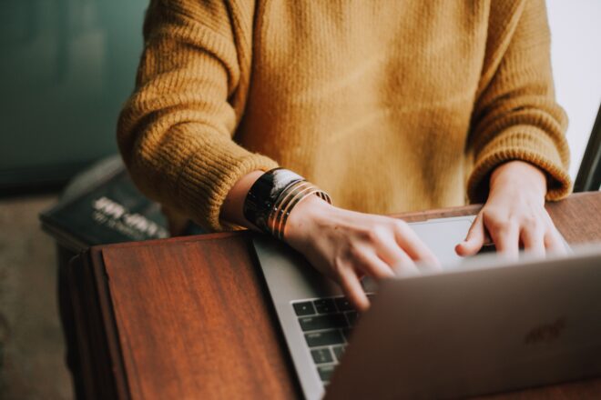 Woman typing on a computer while sitting at table.