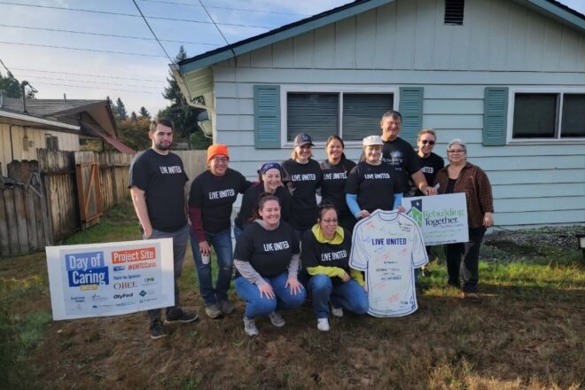 group of volunteers standing in front of green house