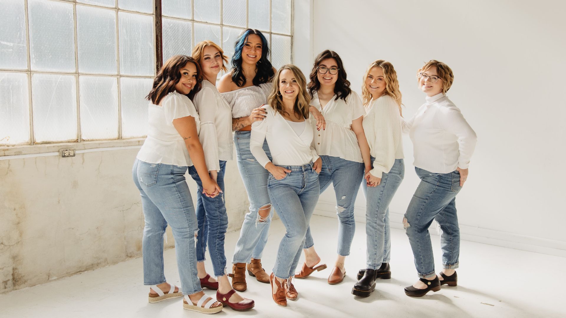 Photo of staff of Salt Hair all dressed in jean pants and white tops posing together.