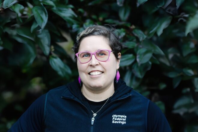 OlyFed employee standing in front of greenery