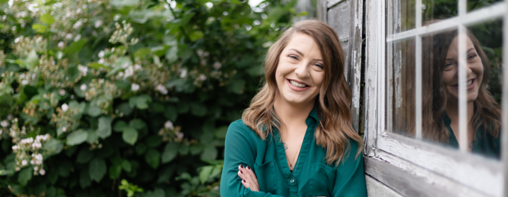 OlyFed Employee standing in front of greenery