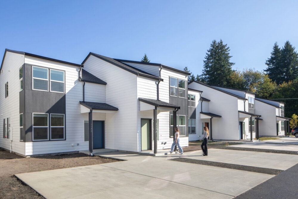 two people walking up to front door of one of five pictured black and white townhomes