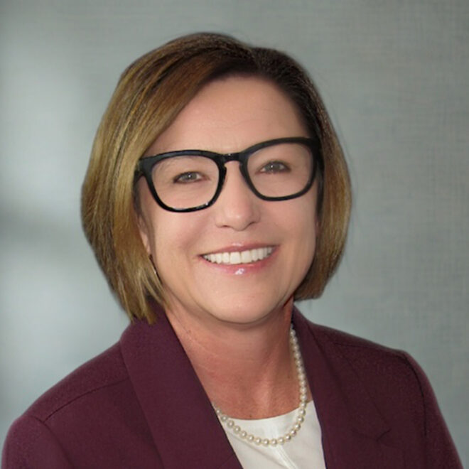 Headshot of woman with short brown hair, red cardigan and white shirt