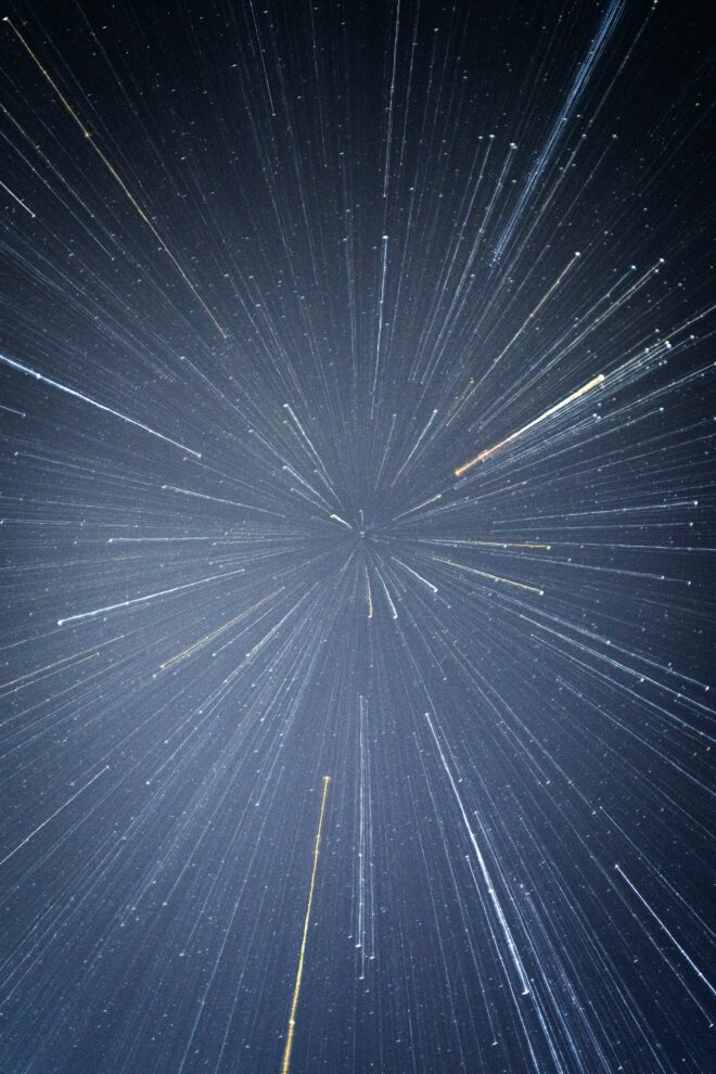 A close-up of a large firework in the gray sky made up of small white streaks
