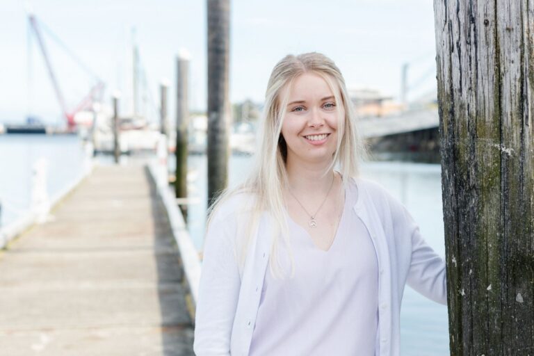 Woman standing on a wood dock on the waterfront.