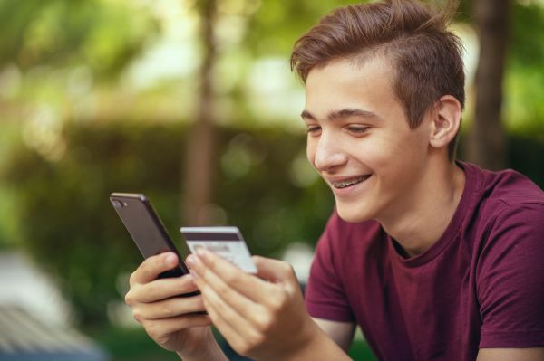 Free Checking Account That Helps Students Learn & Schools Earn. Student using mobile device for online banking.
